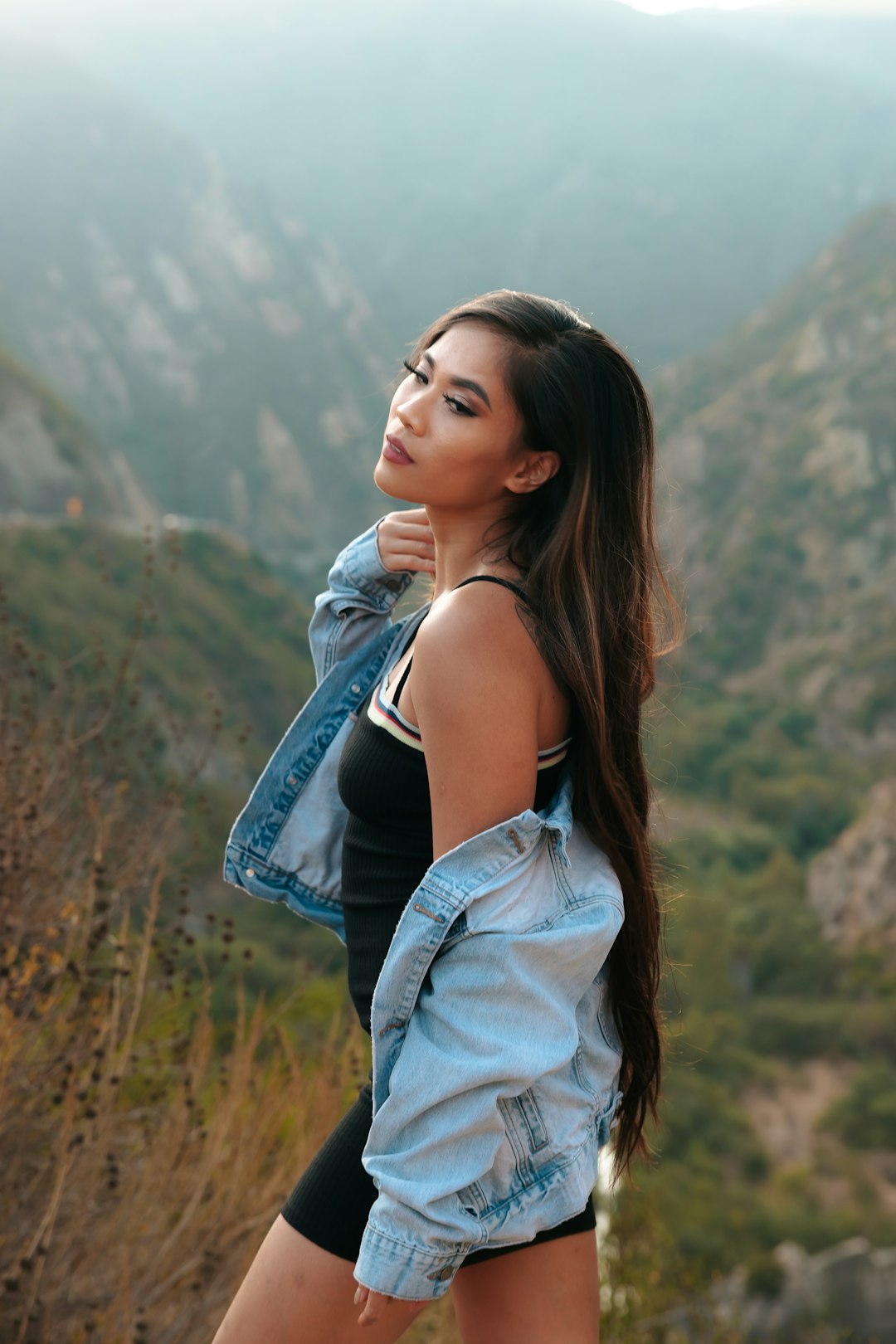 woman in blue denim jacket standing on brown grass field during daytime