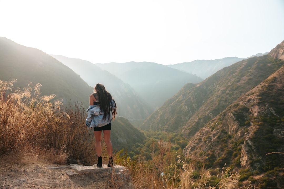 woman in black jacket standing on brown rock during daytime