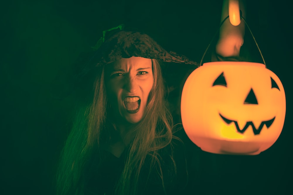 woman with black hair holding jack o lantern