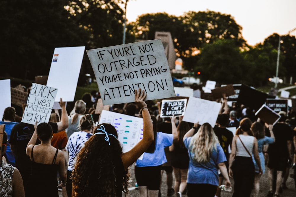 people holding white and black signage during daytime