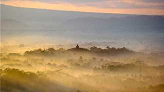 A serene mountain temple at dawn with soft golden light and cosmic symbols subtly overlaid.