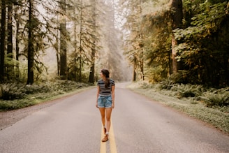 woman in black and white striped long sleeve shirt and blue denim shorts walking on gray