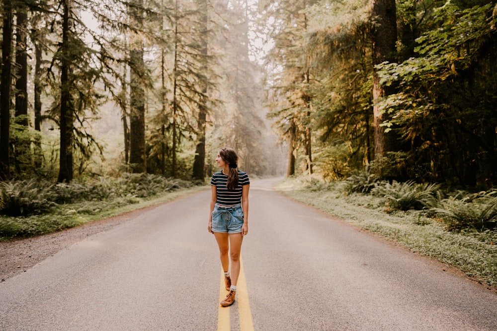 woman in black and white striped long sleeve shirt and blue denim shorts walking on gray