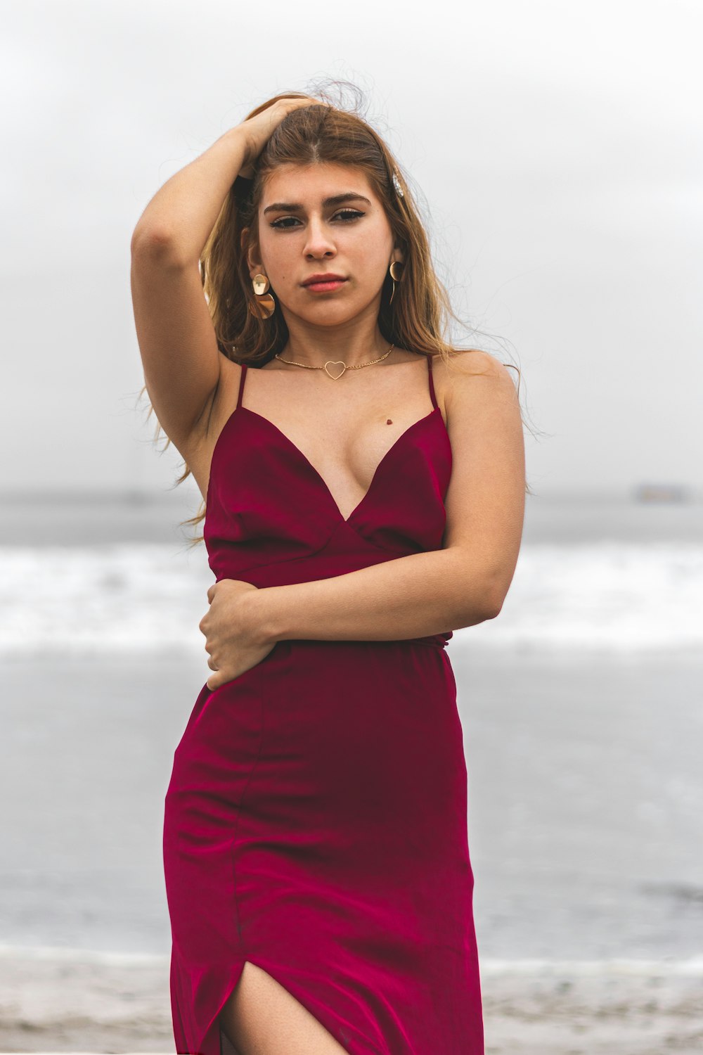 woman in red spaghetti strap dress standing on beach during daytime