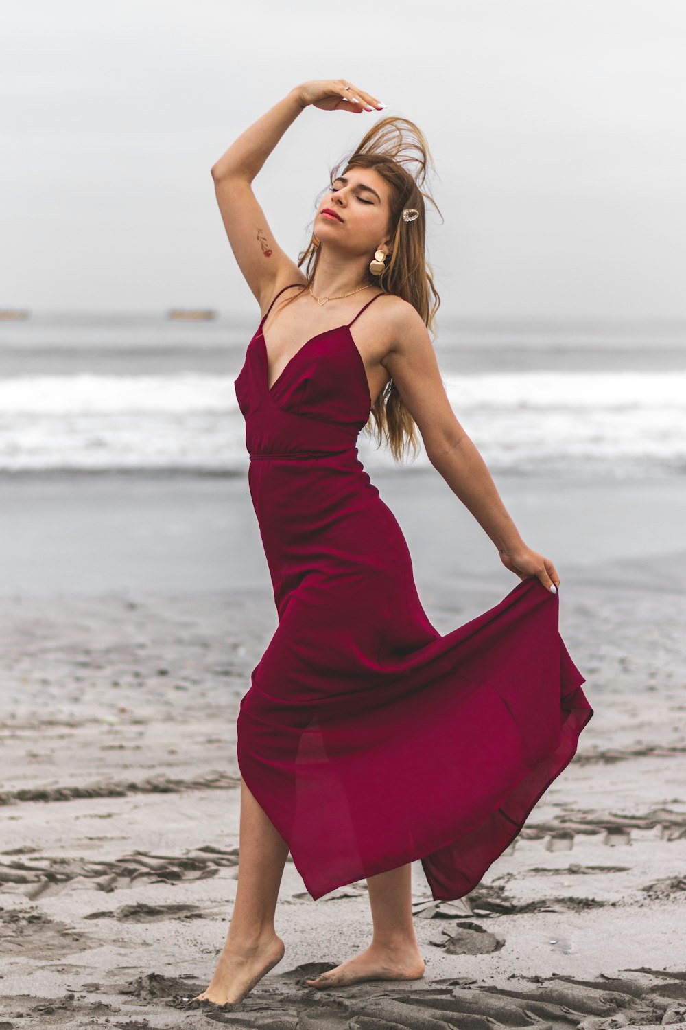 Frau in rotem Spaghettiträgerkleid tagsüber am Strand stehend