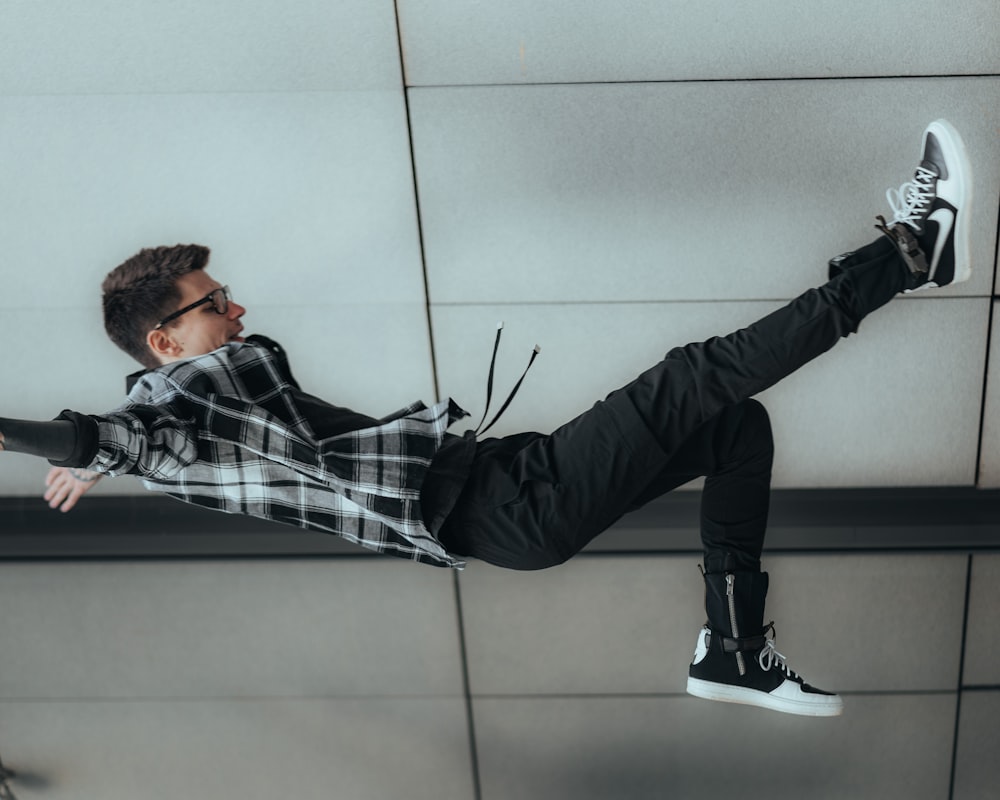 man in black and white plaid dress shirt and black pants lying on floor