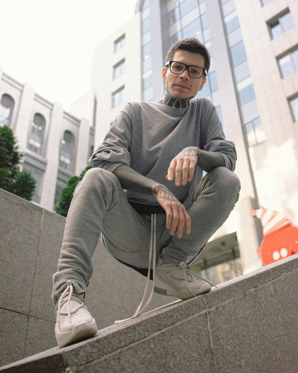 homme en pull gris assis sur un banc en béton gris