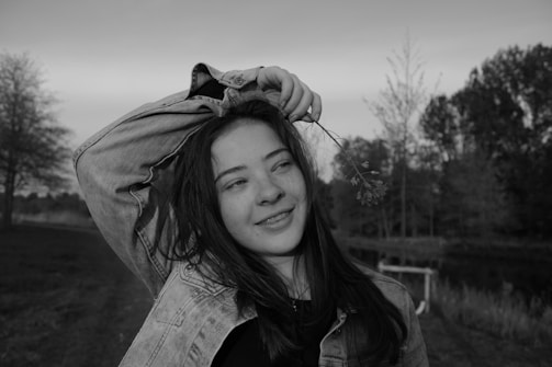 A smiling teenager leading a community meeting outdoors.