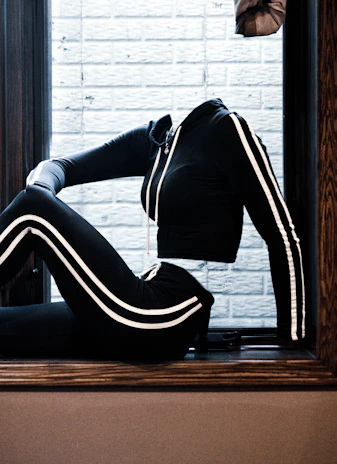 A sleek black and gold training tracksuit displayed on a mannequin against a dark background.