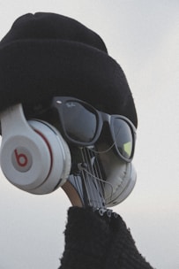 A creative visual of a guitar headstock dressed up with a hat, sunglasses, and headphones, giving it a human-like appearance.