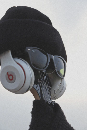 A creative visual of a guitar headstock dressed up with a hat, sunglasses, and headphones, giving it a human-like appearance.