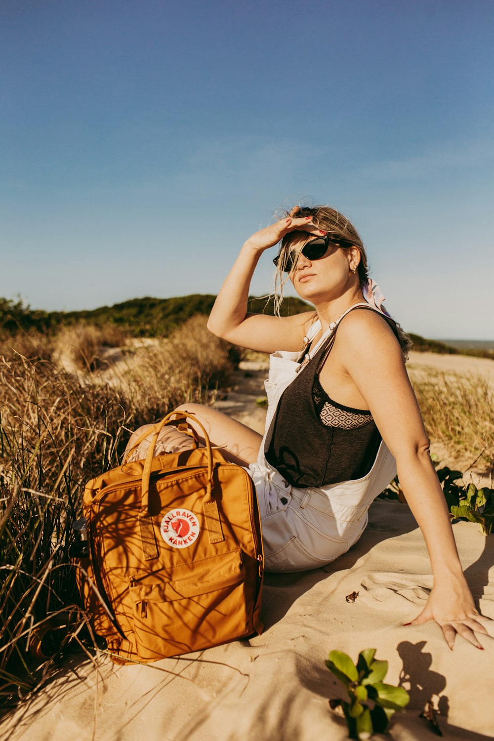 woman in black tank top and beige pants sitting on brown grass field during daytime