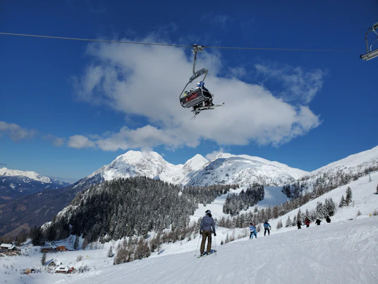 people riding cable car over snow covered mountain during daytime