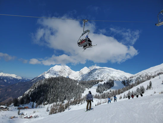 people riding cable car over snow covered mountain during daytime