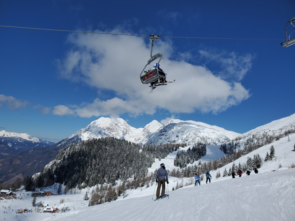 people riding cable car over snow covered mountain during daytime