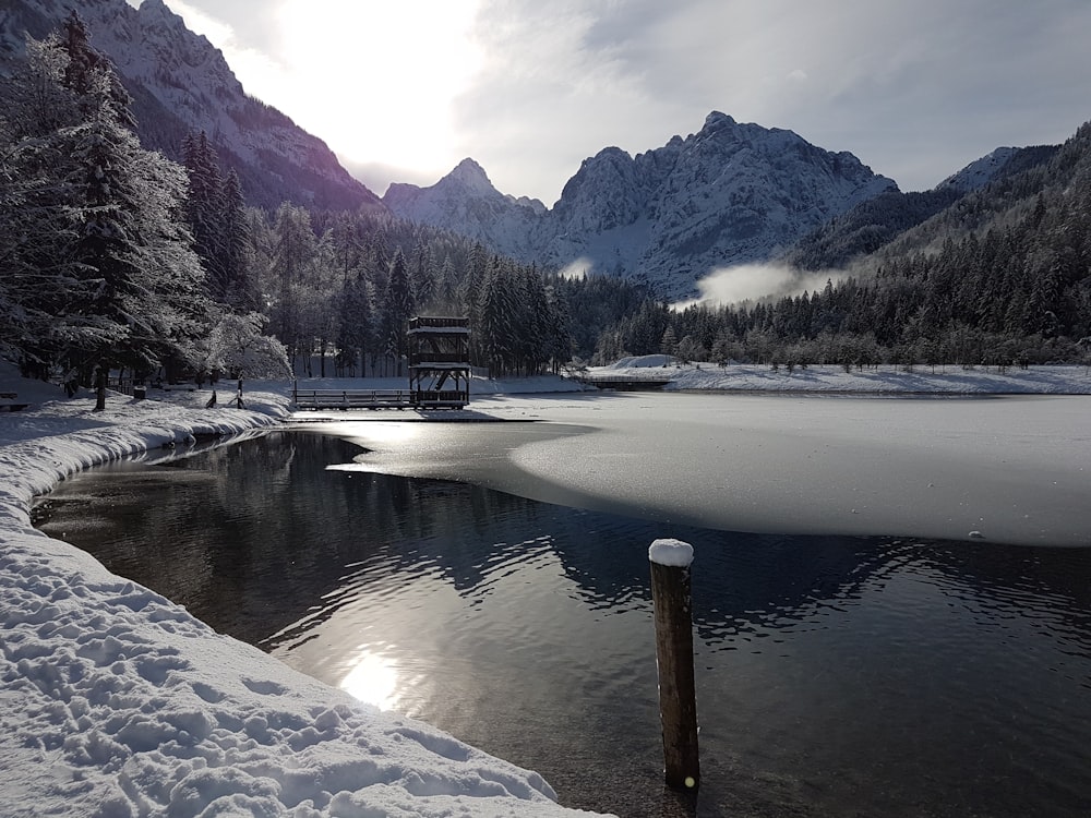 brown wooden bench on snow covered ground near lake and mountain during daytime