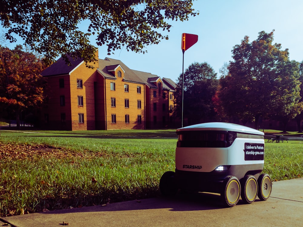 white and black bus on green grass field near brown concrete building during daytime