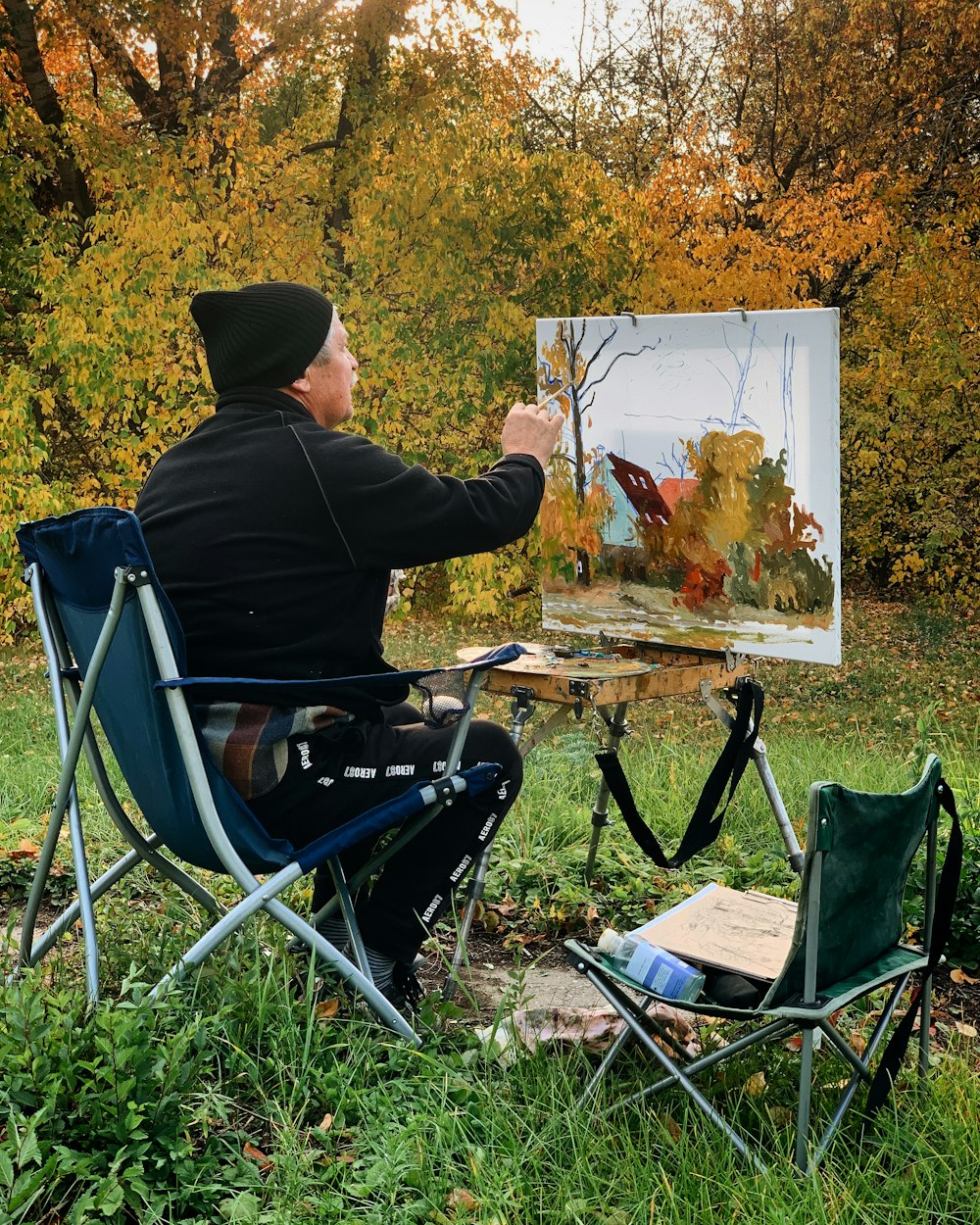 man in black hoodie sitting on blue folding chair