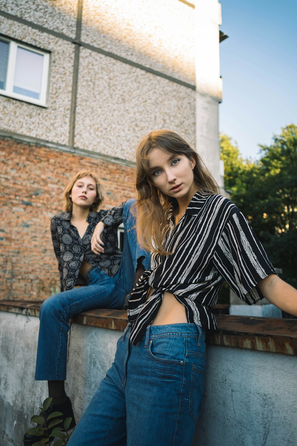 woman in black and white striped long sleeve shirt sitting beside woman in blue denim jeans