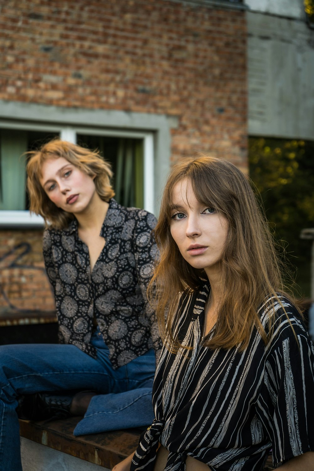 2 women sitting on blue textile