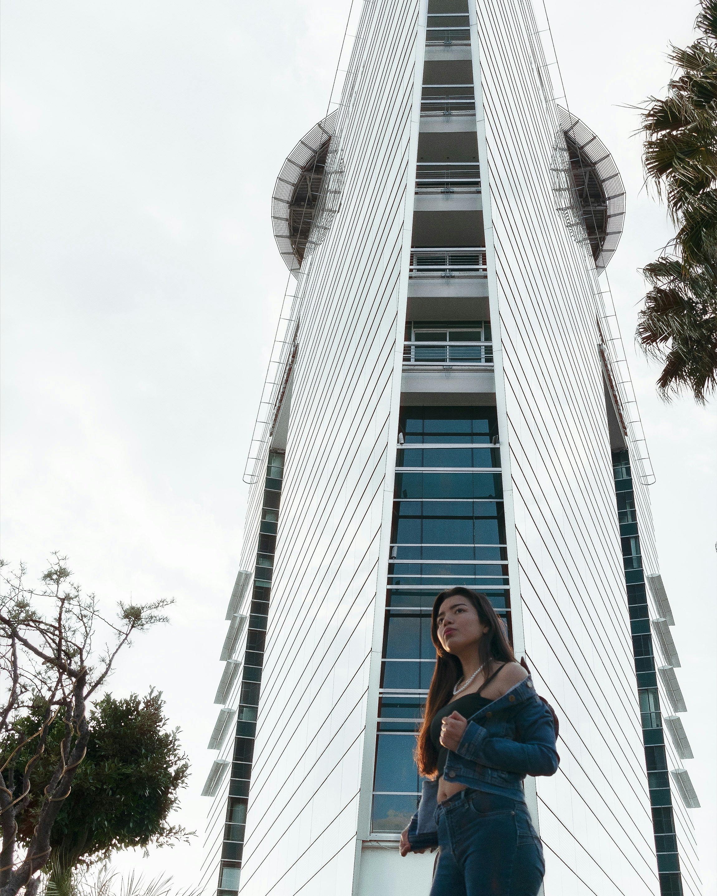 파란색 탱크 탑과 파란색 데님 반바지를 입은 여자가 파란색 콘크리트 벤치에 앉아 있다