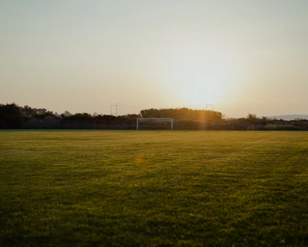 A focused athlete training on the field under golden sunset light.