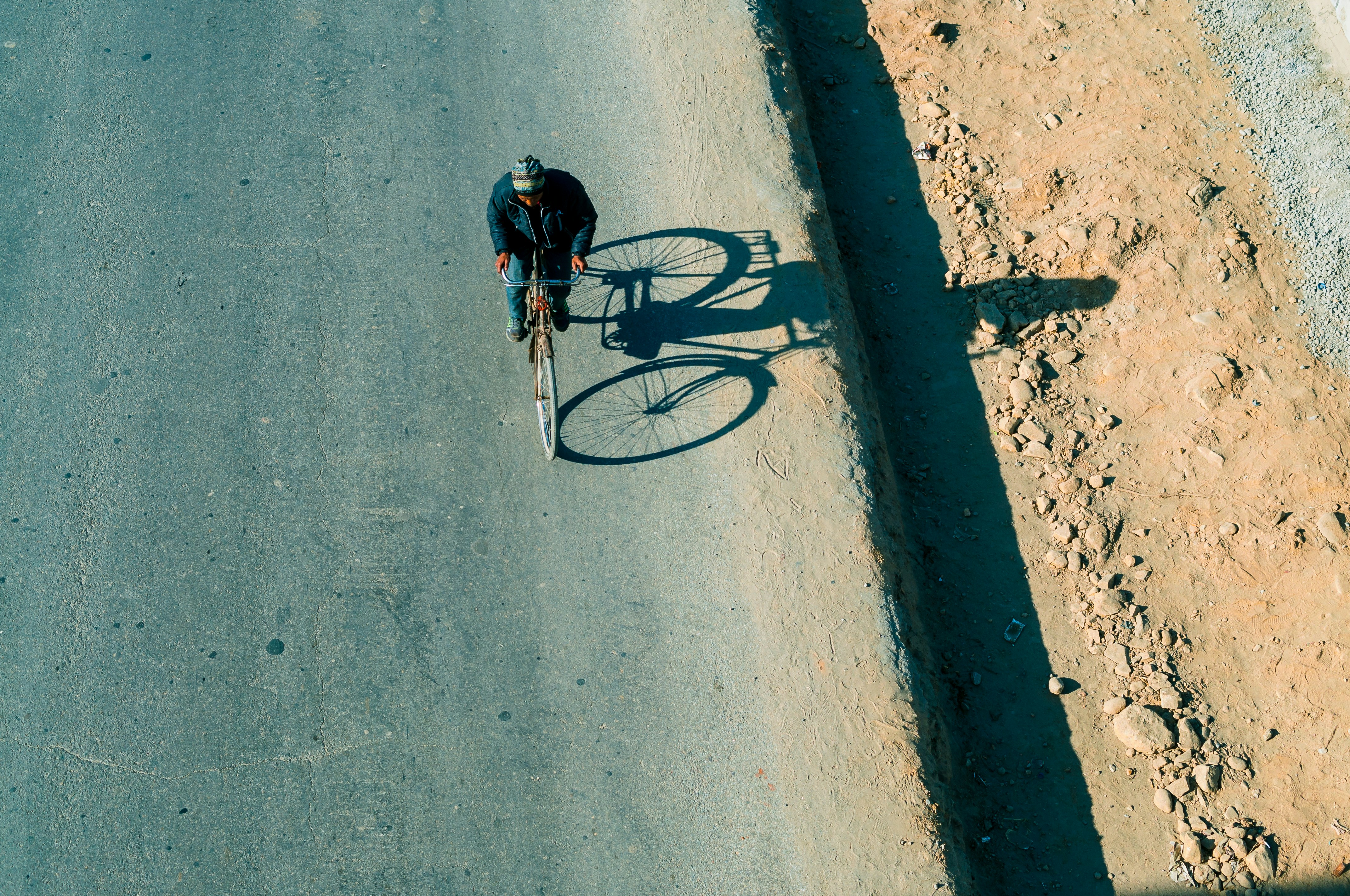 person riding bicycle on gray concrete road during daytime