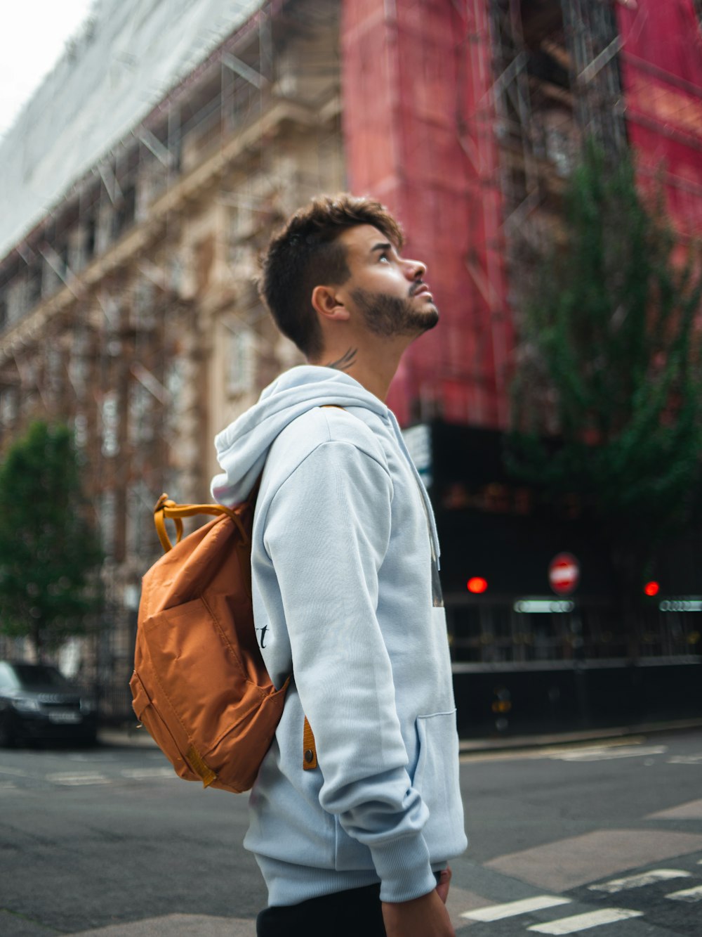 man in white dress shirt with brown backpack standing on sidewalk during daytime