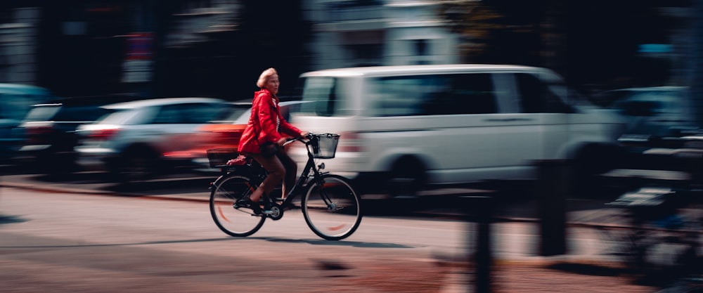 낮 동안 도로에서 자전거를 타는 빨간 재킷을 입은 남자