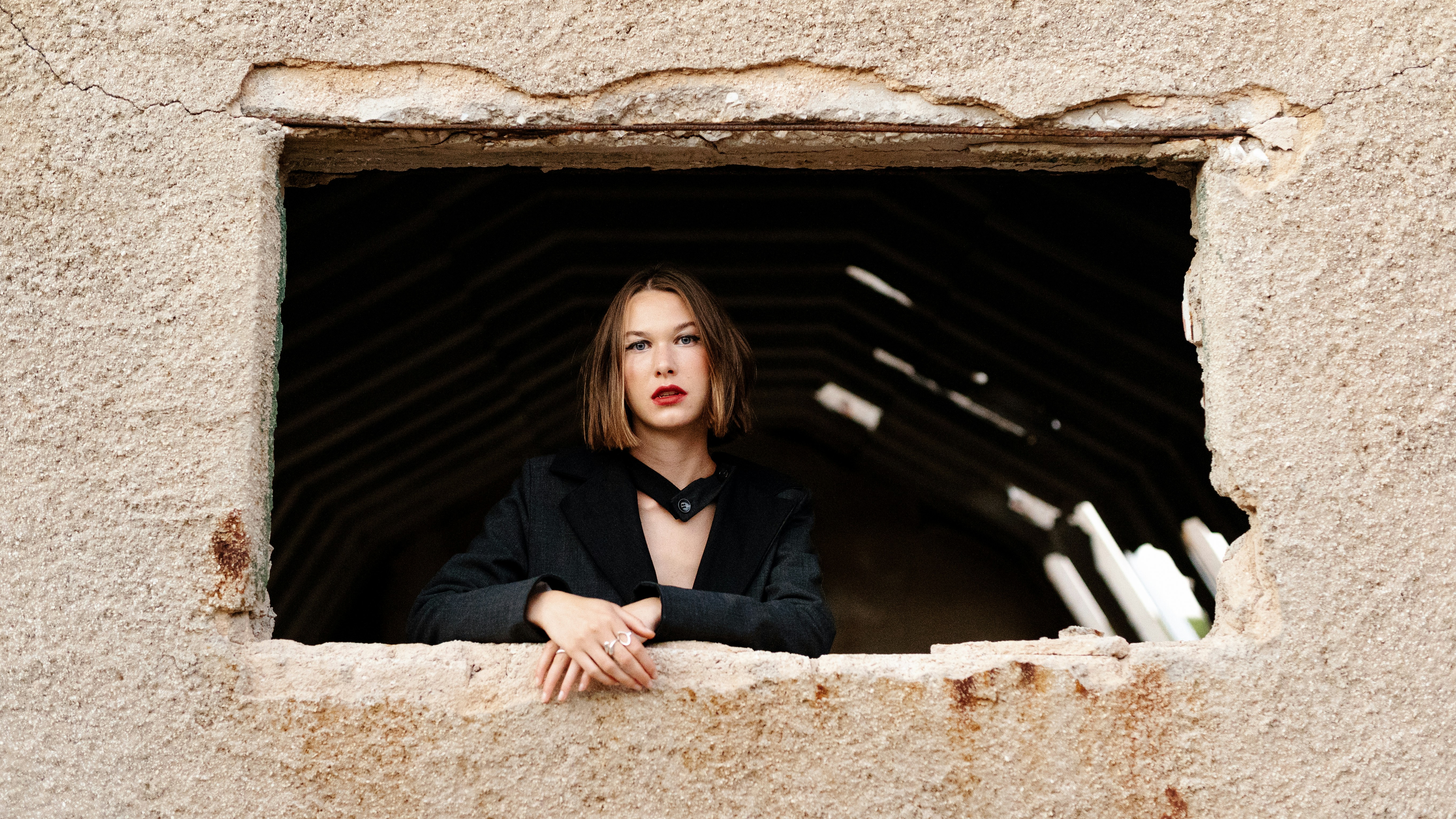 Frau im schwarzen Langarmhemd sitzt auf braunem Felsen