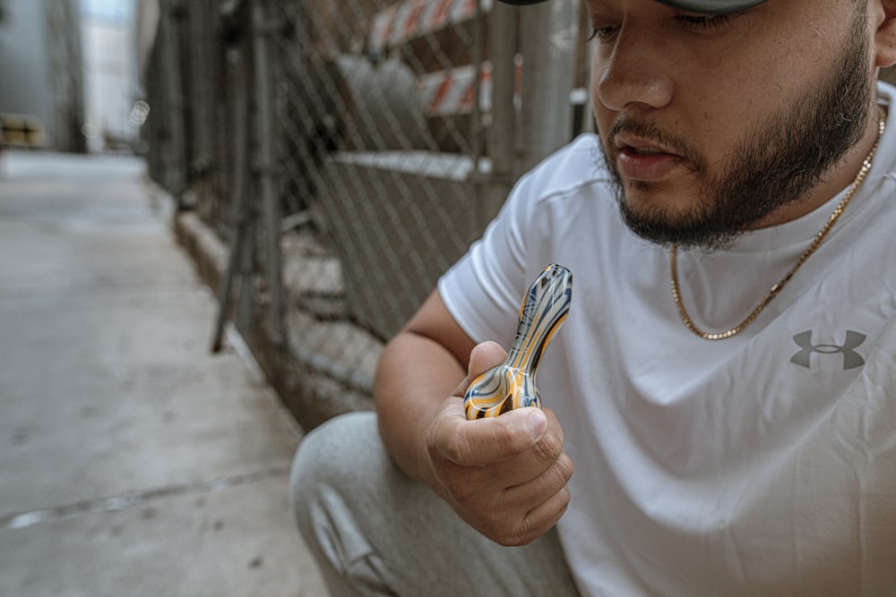 man in white crew neck t-shirt holding yellow and black stripe glass