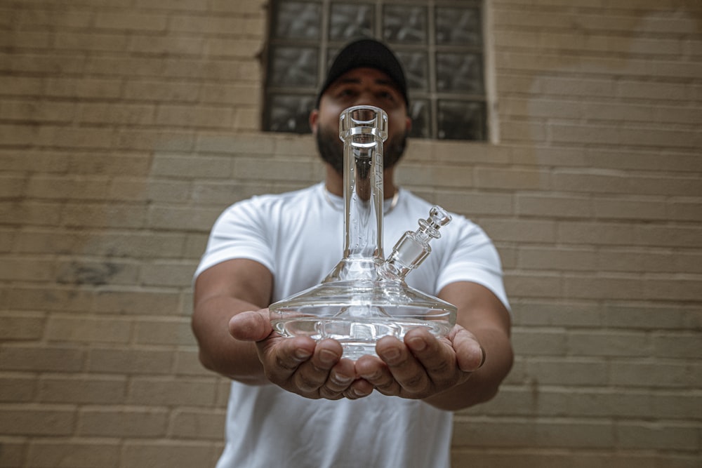 man in white crew neck t-shirt holding clear glass bottle