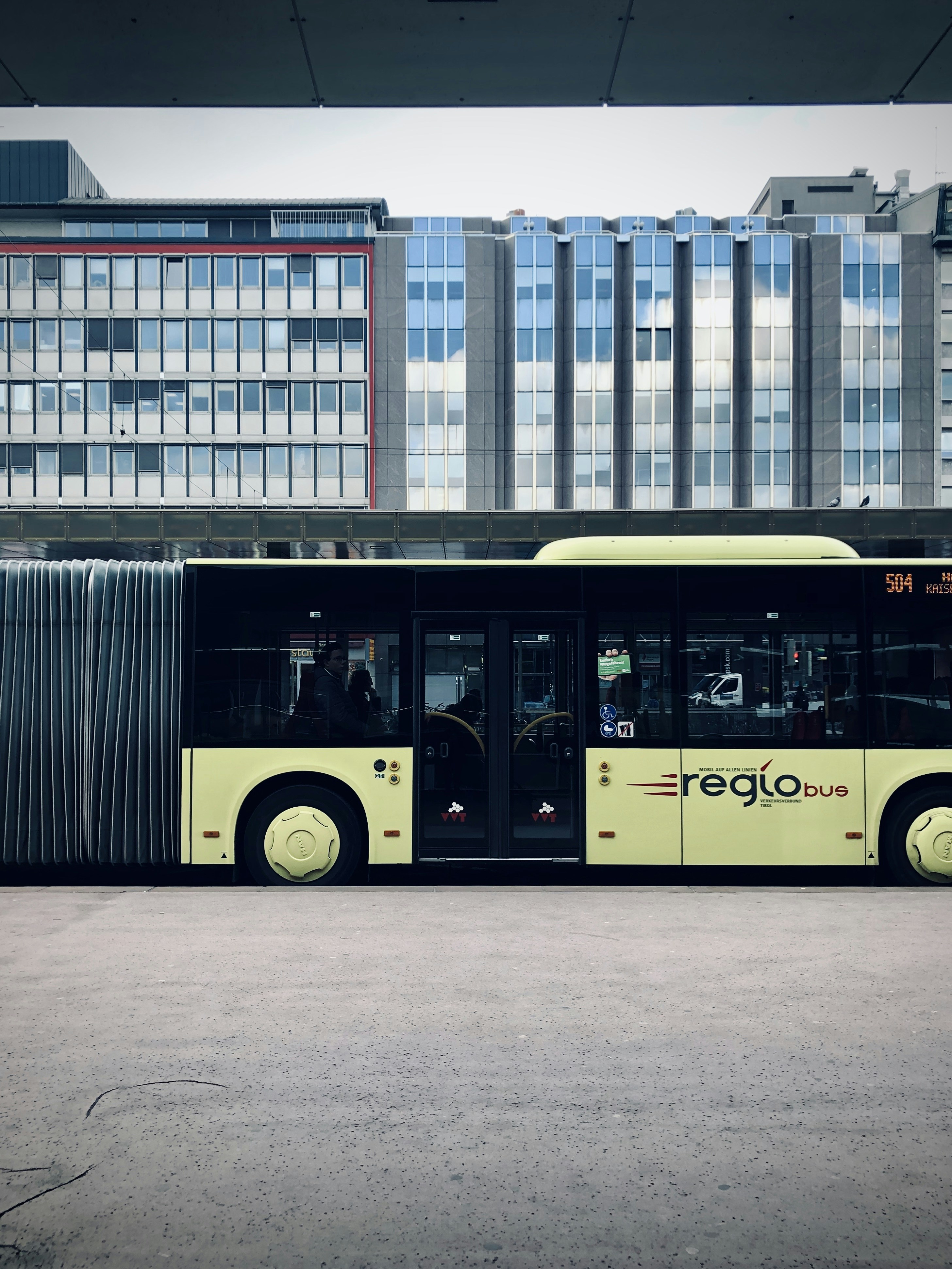 yellow bus in front of white concrete building during daytime