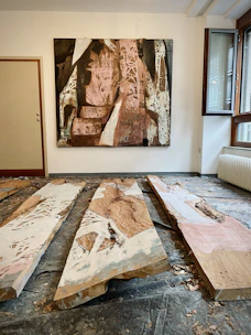 A bright, abstract painting leaning against a white wall with natural light.