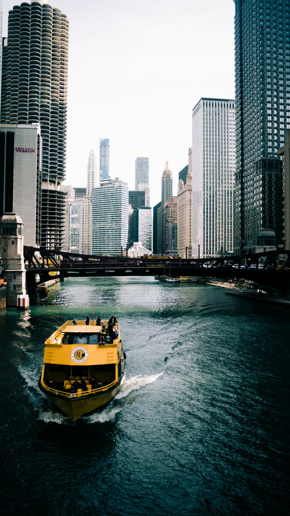 barco amarelo e preto na água perto de edifícios altos durante o dia