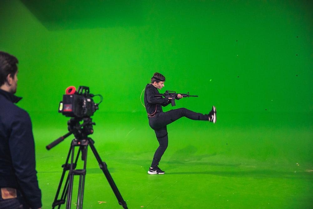 man in black jacket and black pants holding black dslr camera