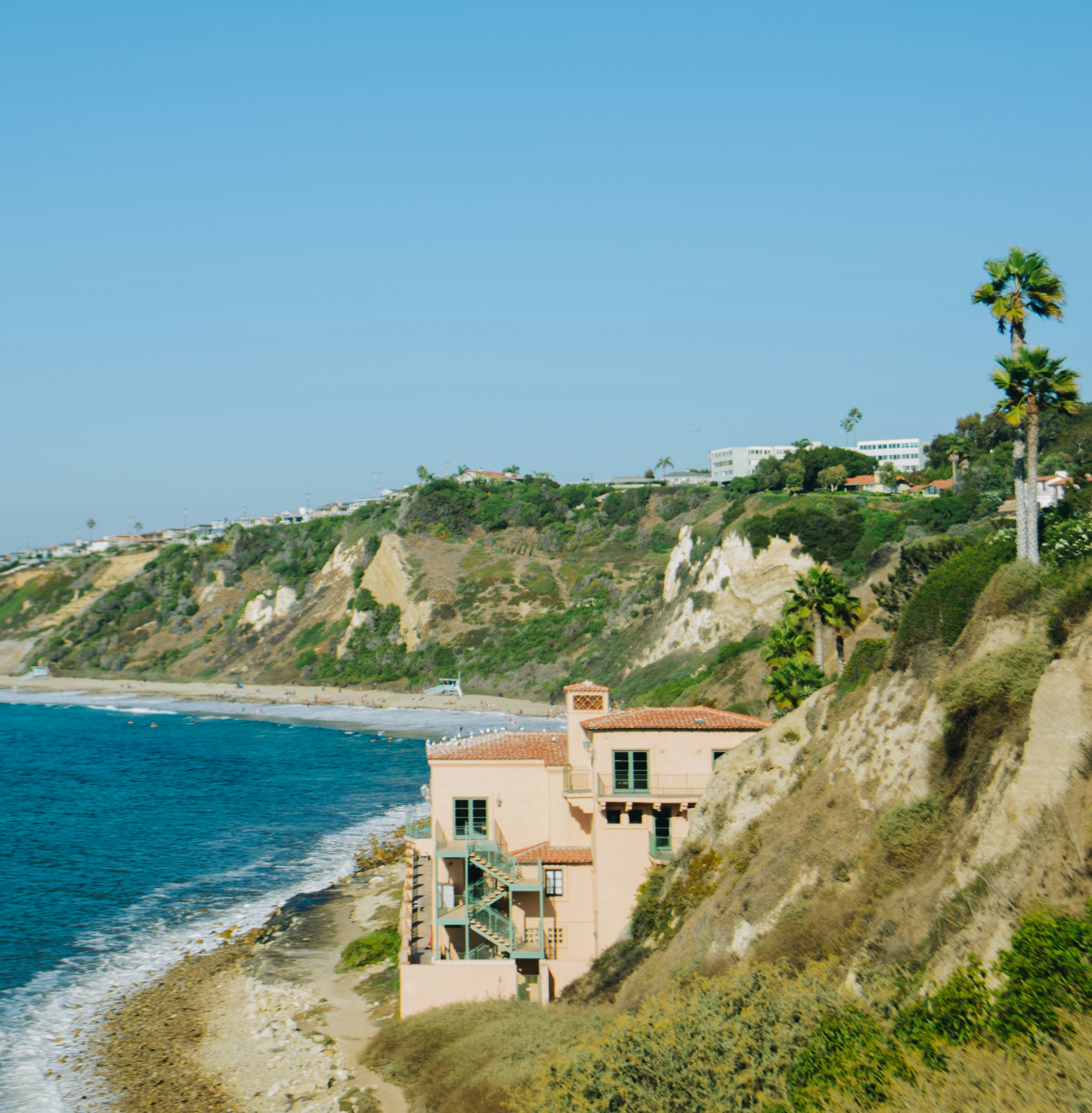 brown concrete building on cliff by the sea during daytime