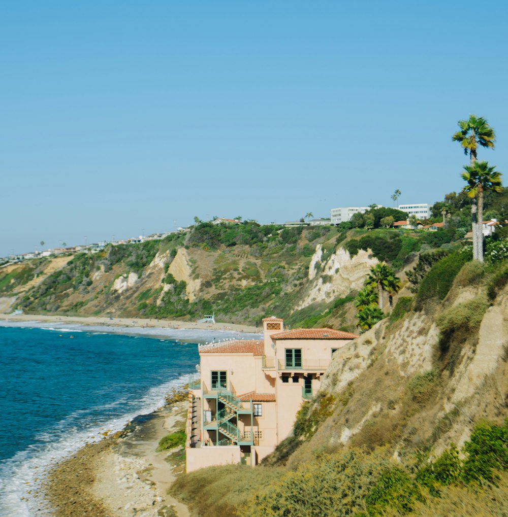 brown concrete building on cliff by the sea during daytime