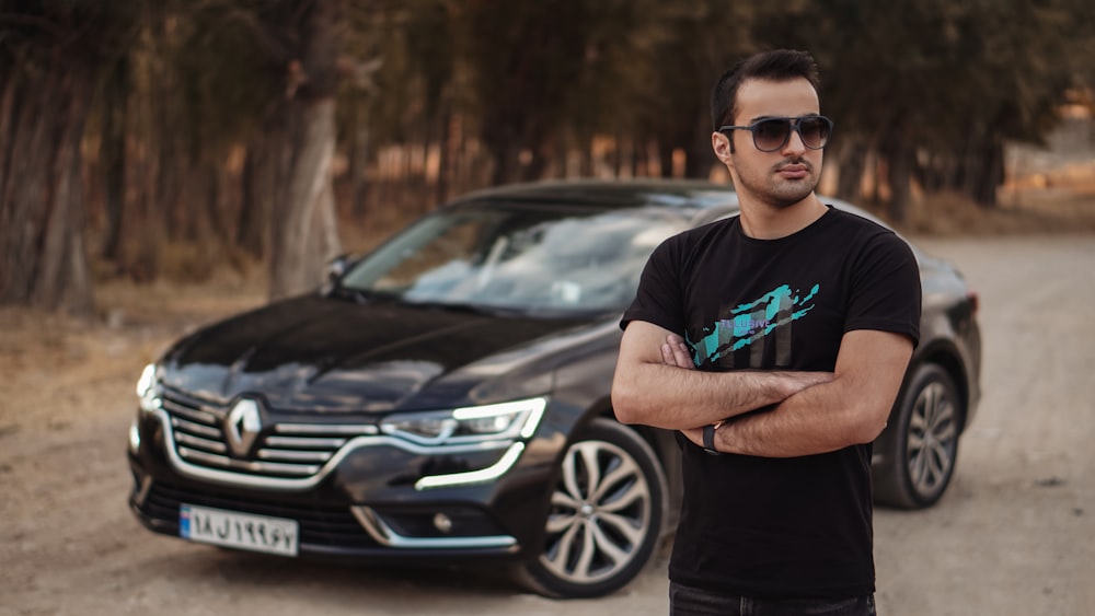 man in black crew neck t-shirt standing beside black mercedes benz car