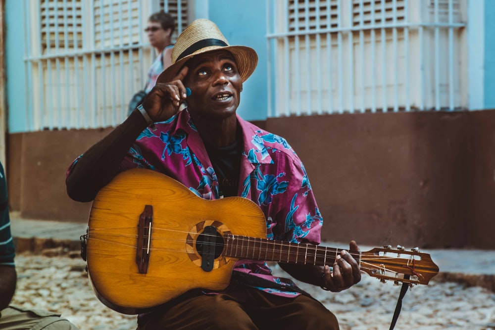 man in red and blue button up shirt playing guitar