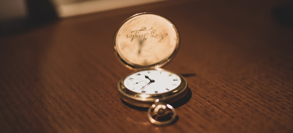 silver round analog watch on brown wooden table