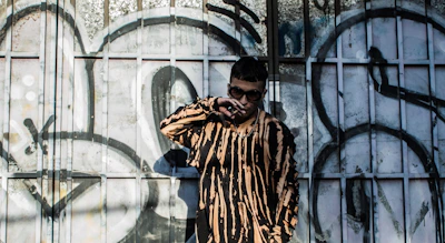 A model striking a pose in an oversized graphic tee against a graffiti wall backdrop.