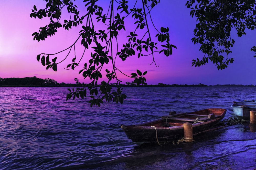 brown boat on body of water during sunset