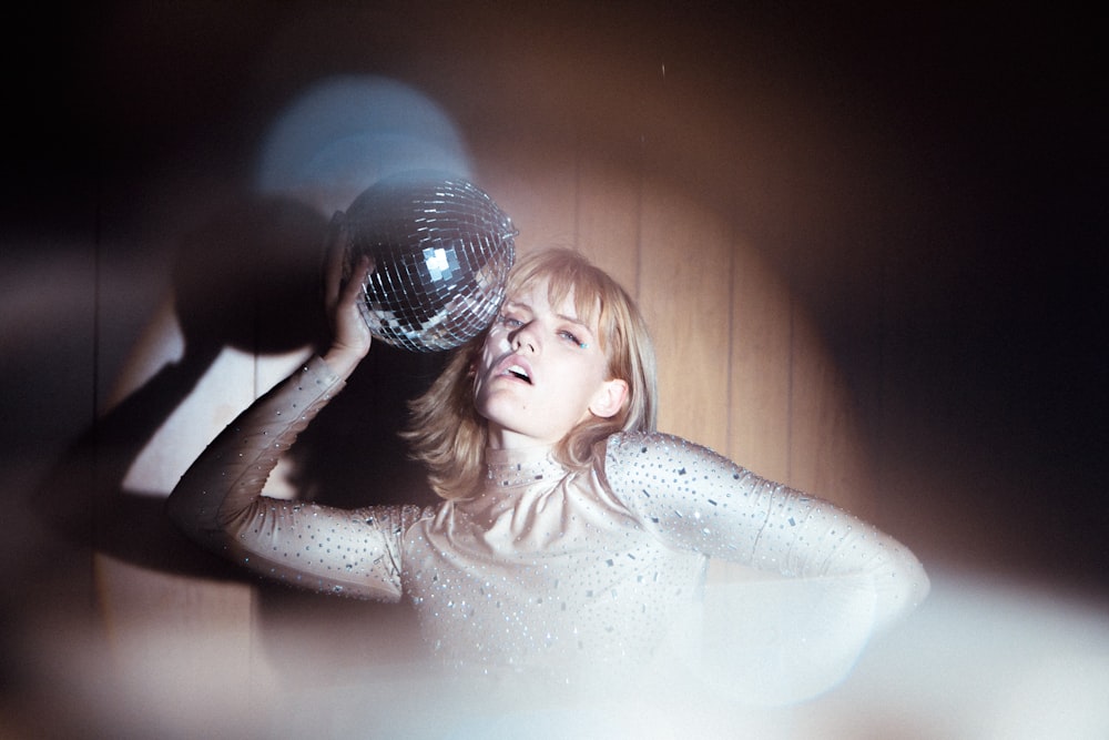 girl in white tank top holding clear glass ball