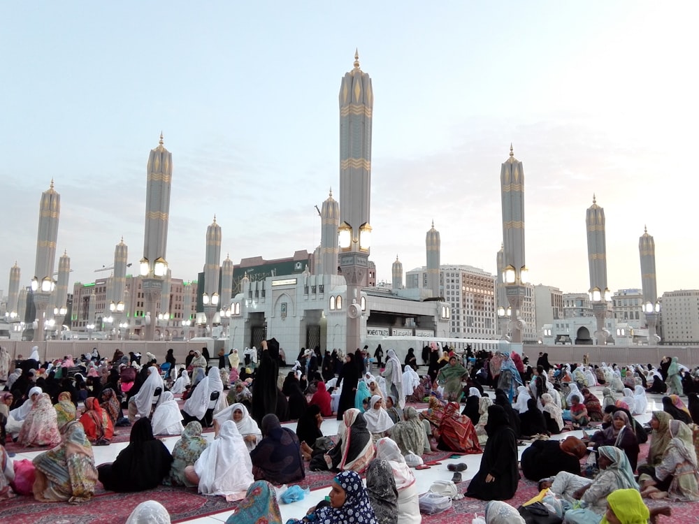 people sitting on red carpet near white concrete building during daytime