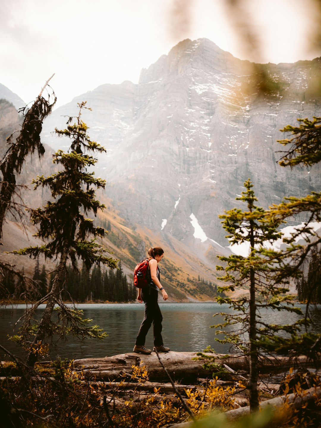 woman in red jacket and black pants standing on river during daytime