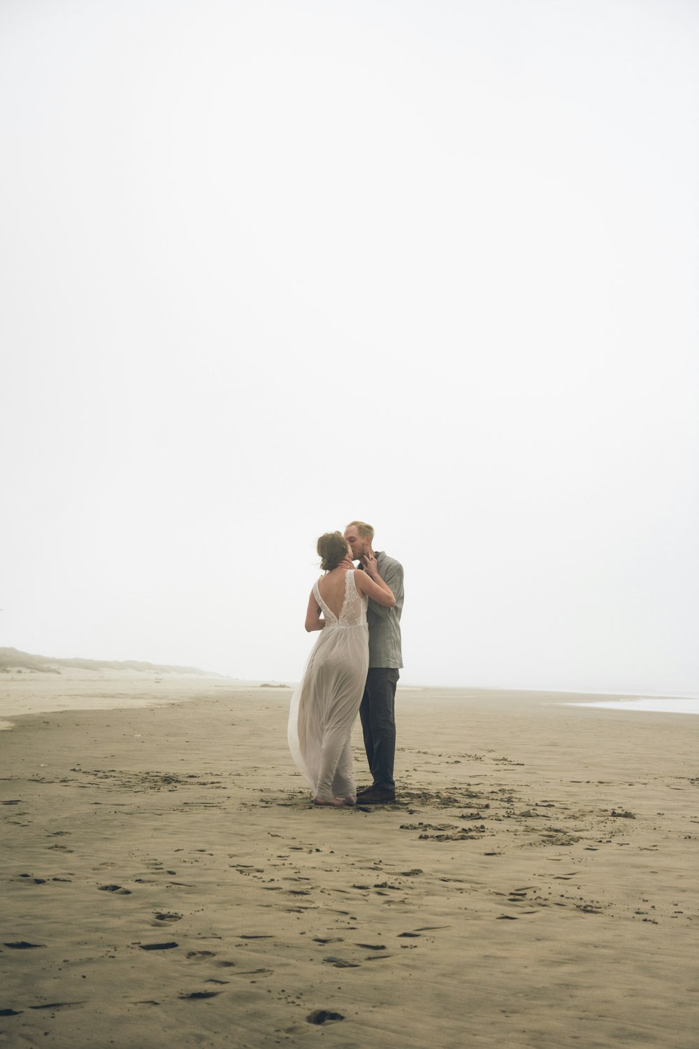 man and woman kissing on brown sand during daytime