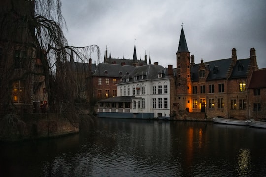 brown and white concrete building beside river during daytime in Belfry of Bruges Belgium