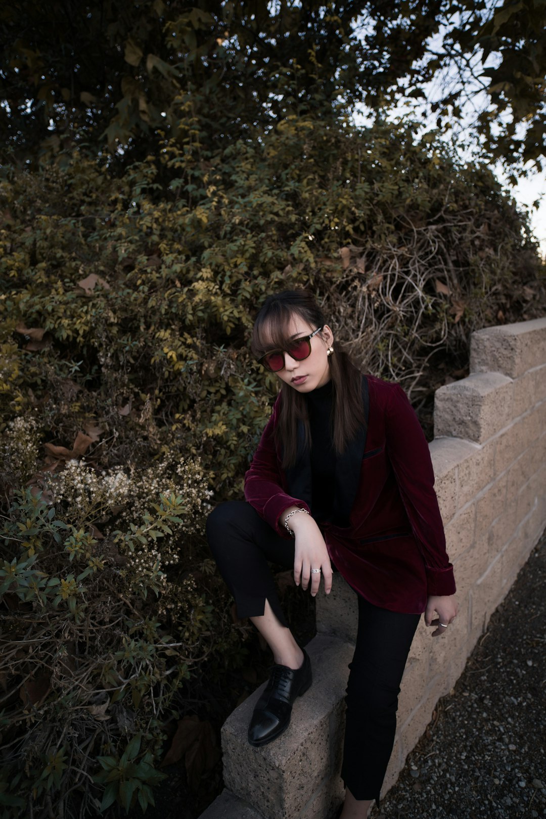 woman in red cardigan sitting on concrete bench