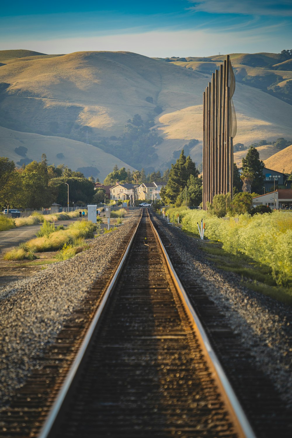 train rail near green grass field and mountain during daytime